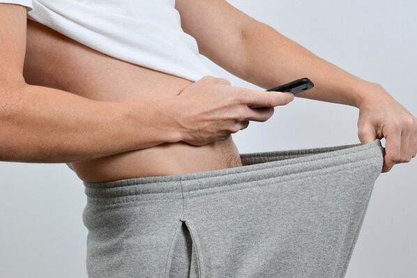 мужчына глядзіць у штаны на павялічаны пеніс